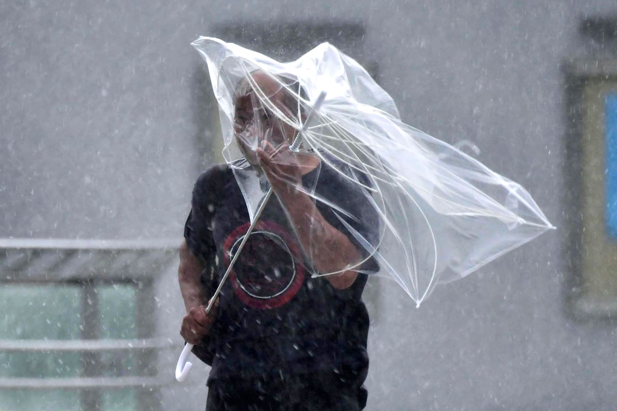 Un hombre pasa problemas con su sombrilla a causa de los fuertes vientos generados por un tifón, el lunes 9 de septiembre de 2019 en la ciudad de Iwaki, Fukushima, en el norte de Japón. (Kyodo News via AP)