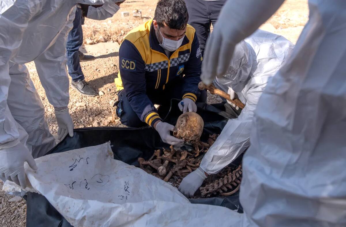 Miembros de los Cascos Blancos de Siria trabajan en una fosa común donde se encontraron restos humanos, presuntamente de civiles asesinados por el régimen derrocado de Bashar al-Assad. El hallazgo ocurrió en la zona del Puente de Bagdad, en las afueras de Damasco, Siria, el martes. Emin Sansar/Anadolu/Getty Images.