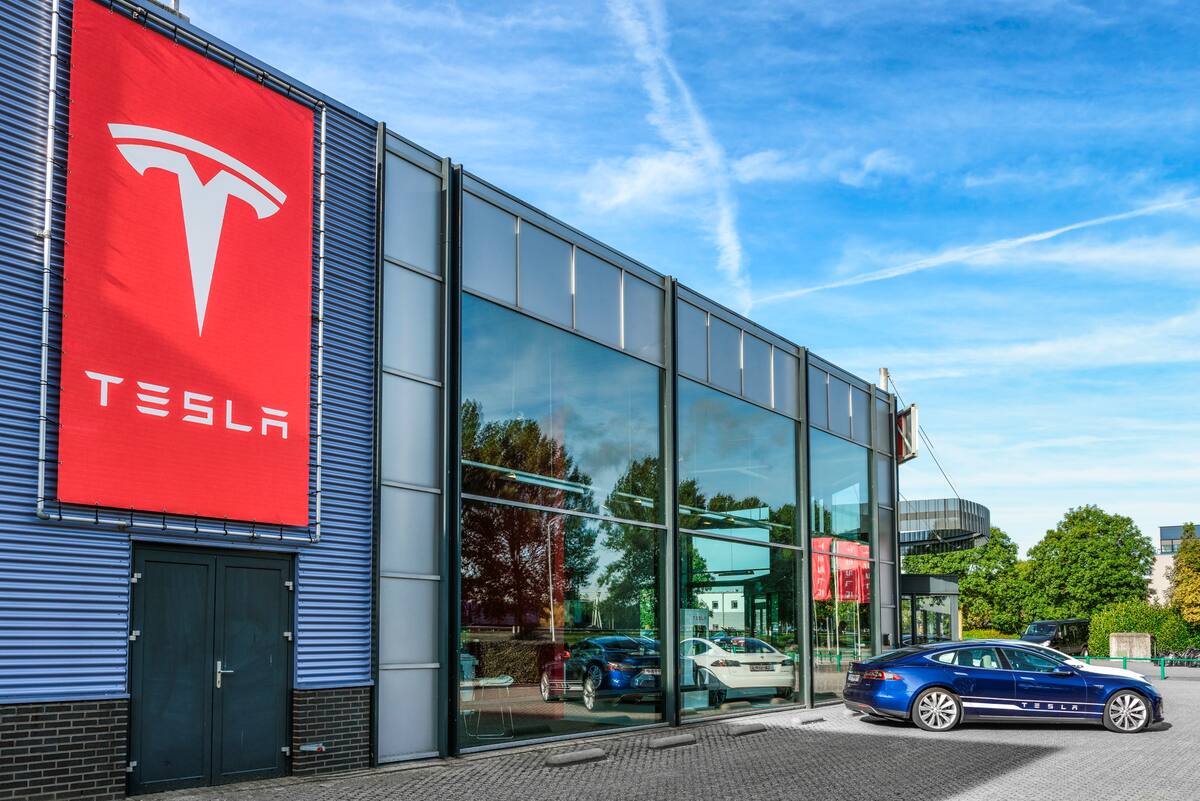 Blue and white Tesla Model S full electric luxury car parked outside a dealership. The Tesla Model S is a full-sized plug-in electric five-door, luxury liftback, produced by the American automotive company Tesla Motors.
