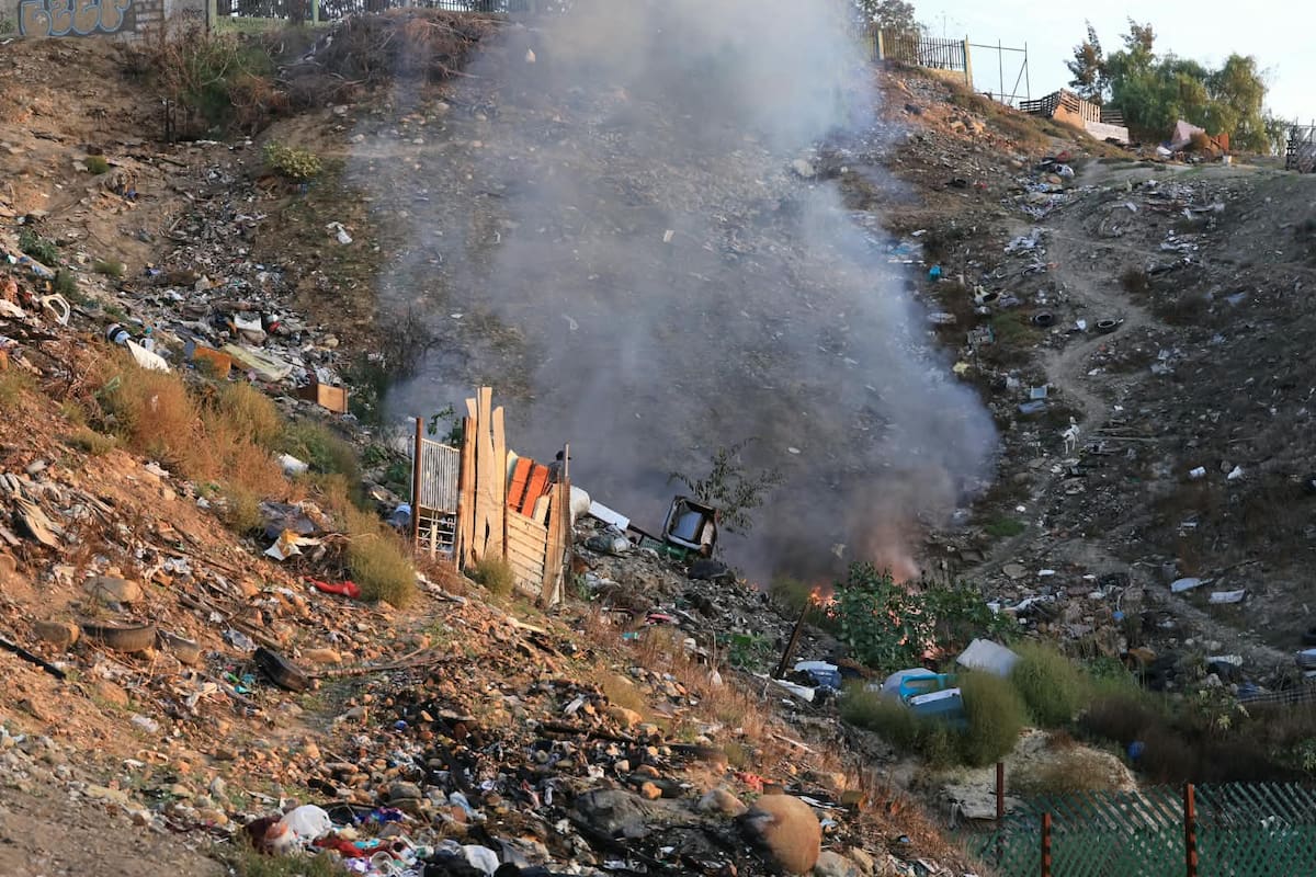 Un hombre en situación de calle sofocó con cubetas de agua un incendio de basura en la colonia Anexa Buena Vista, en Tijuana. Foto: Sergio Ortiz