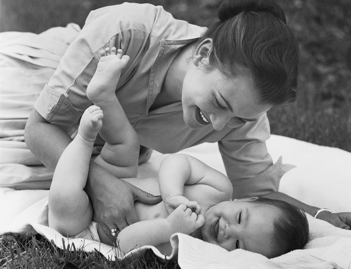 Happy retro mother and baby lying on blanket in backyard