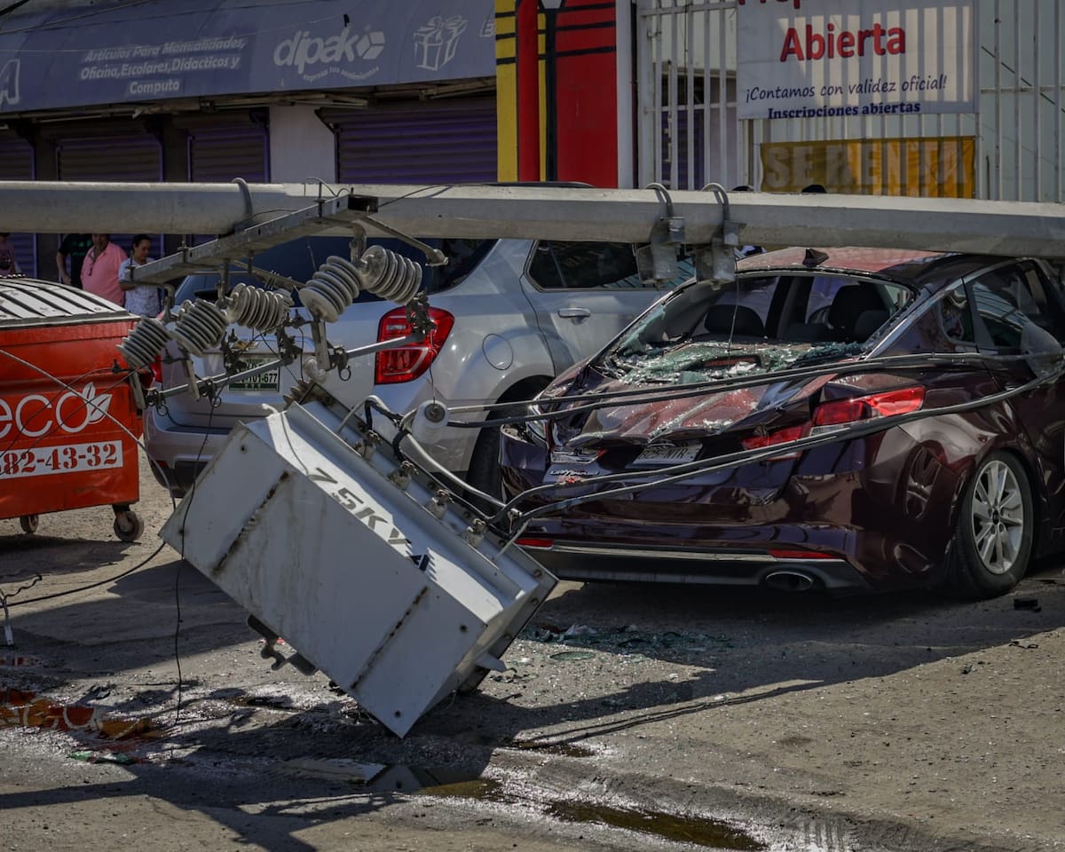 Un poste de concreto cae sobre un vehículo estacionado después de que maquinaria agrícola derribó cableado eléctrico y de telecomunicaciones sobre la avenida Río Champotón. El incidente provocó cierres viales y afectaciones en el suministro eléctrico. (Foto: Javier Gallegos)