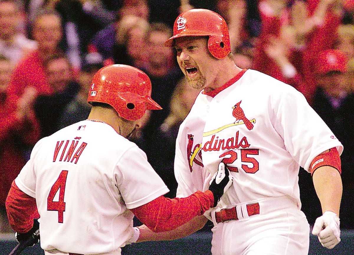 Mark McGwire (derecha) celebra haber conectado un cuadrangular con su compañero de los St. Luis Cardinals, Fernando Viña. (AP Photo/Tom Gannam)