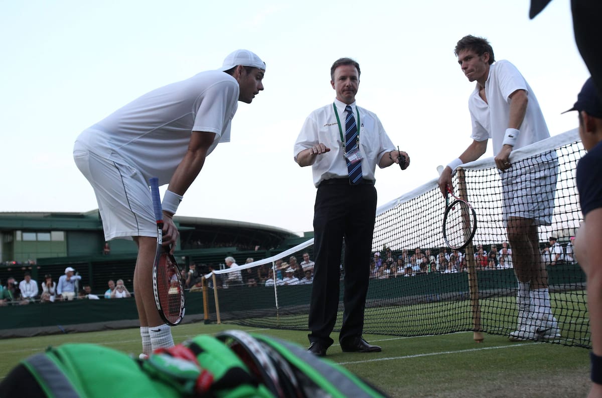 El juez Soeren Friemel, al centro, da por suspendido el épico partido de singles varonil entre el estadounidense John Isner, a la izquierda, y el francés Nicolas Mahut, debido a la falta de luz, en el All England Lawn Tennis Championships de Wimbledon, el miércoles 23 de junio de 2010. (Foto AP: Alastair Grant)