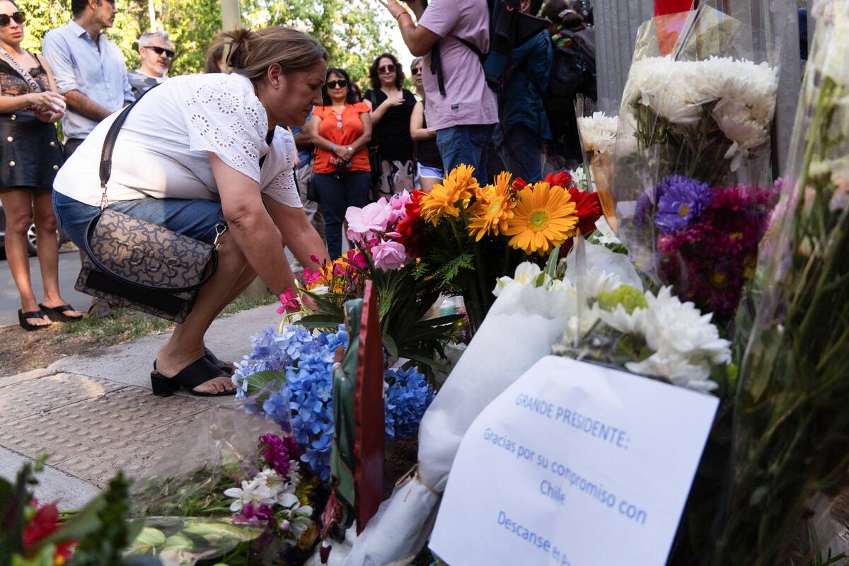 Personas dejan flores en la casa del fallecido expresidente chileno Santiago Piñera en Santiago, Chile, tras darse a conocer la noticia de su fallecimiento en un accidente de helicóptero el martes 6 de febrero de 2024. (AP Foto/Matías Basualdo)