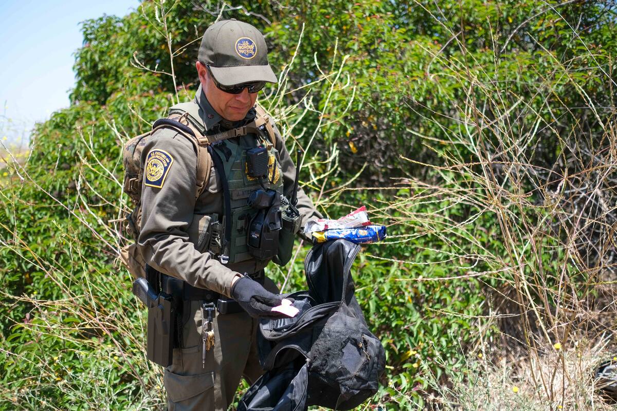 Un agente de la Patrulla muestra el contenido de una mochila abandonada por un migrante que contenía atún, pasta
de dientes, ropa y galletas.