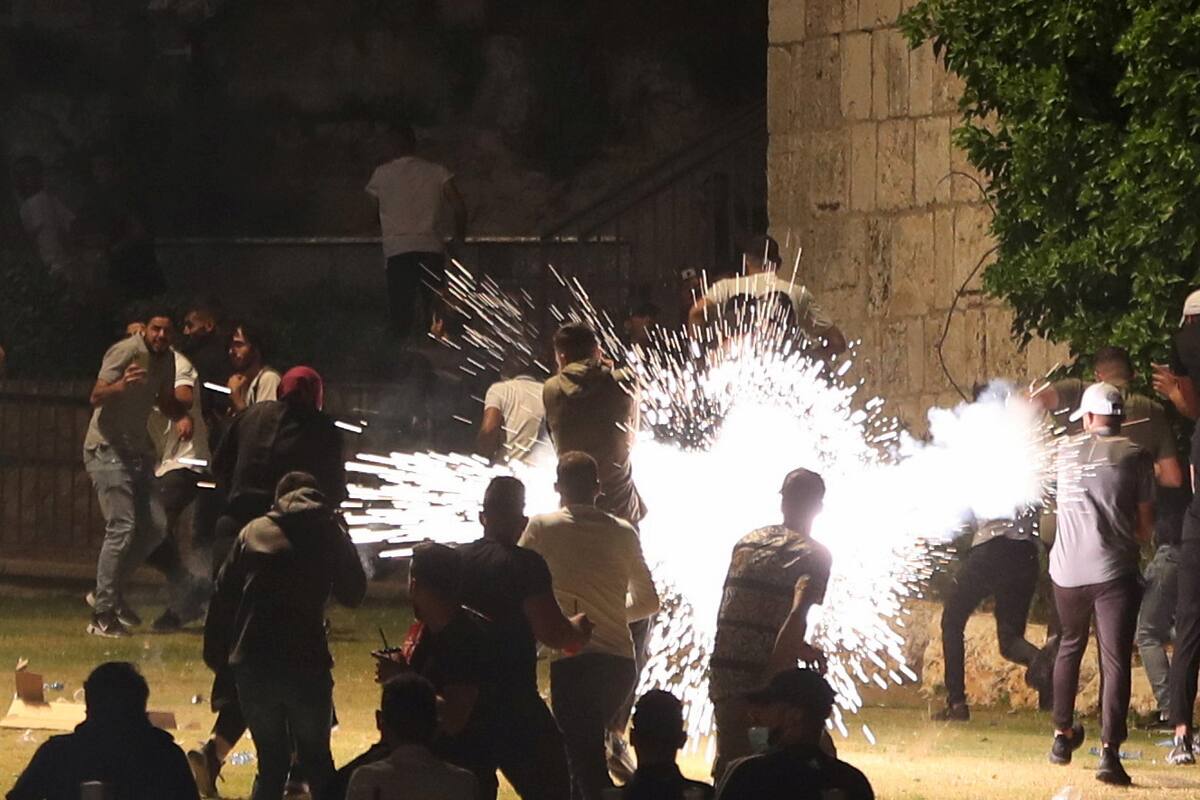 Palestinos reaccionan mientras la policía israelí dispara una granada aturdidora durante los enfrentamientos durante Laylat al-Qadr, en el mes sagrado del Ramadán, en la Ciudad Vieja de Jerusalén. 8 de mayo de 2021. REUTERS/Ronen Zvulun