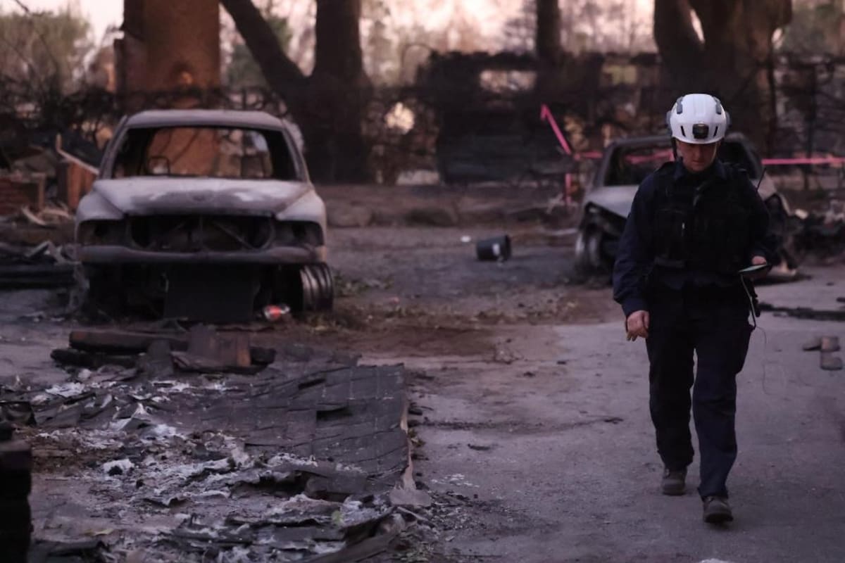 Un miembro de búsqueda y rescate del condado de Marin camina junto a un automóvil quemado por una carretera desierta destruida por el incendio de Eaton en Altadena el 11 de enero de 2025. | Crédito: REUTERS