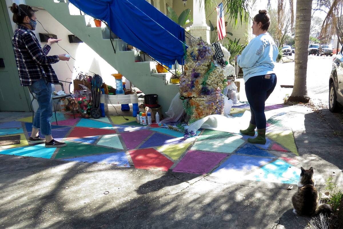 Jessica Spencer, izquierda, y Carley Sercovich decoran la casa de Sercovich como carroza de Mardi Gras en el barrio de Algiers Point, en Nueva Orleáns, el viernes 15 de enero de 2021. Con la cancelación de los tradicionales desfiles de Mardi Gras debido a la pandemia de coronavirus, miles alrededor de la ciudad han decorado sus casas para celebrar el Carnaval. (AP Foto/Janet McConnaughey)