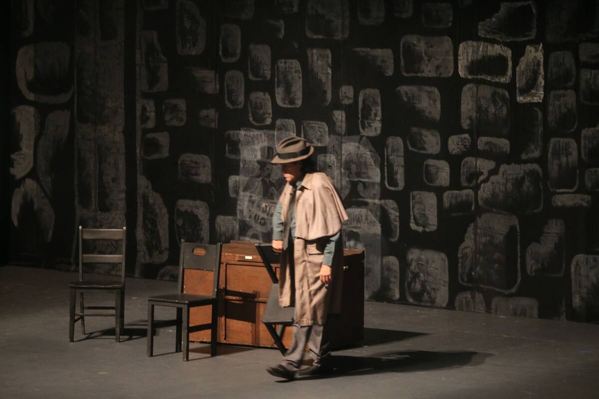 La representación teatral se presenta con una modesta escenografía, tres sillas, un escritorio, un par de prendas colgadas a los laterales y una cortina traslúcida adornaban la tarima.