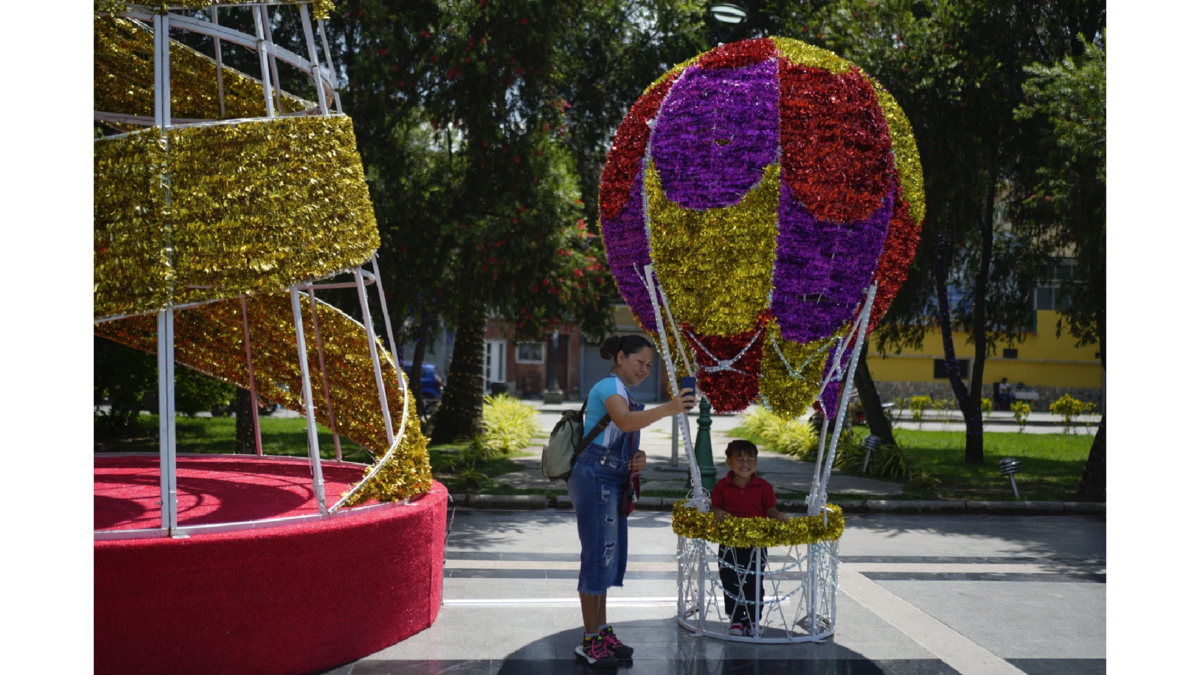 Una mujer se toma una selfie con su hija entre decoraciones navideñas en las calles de Venezuela. | AP