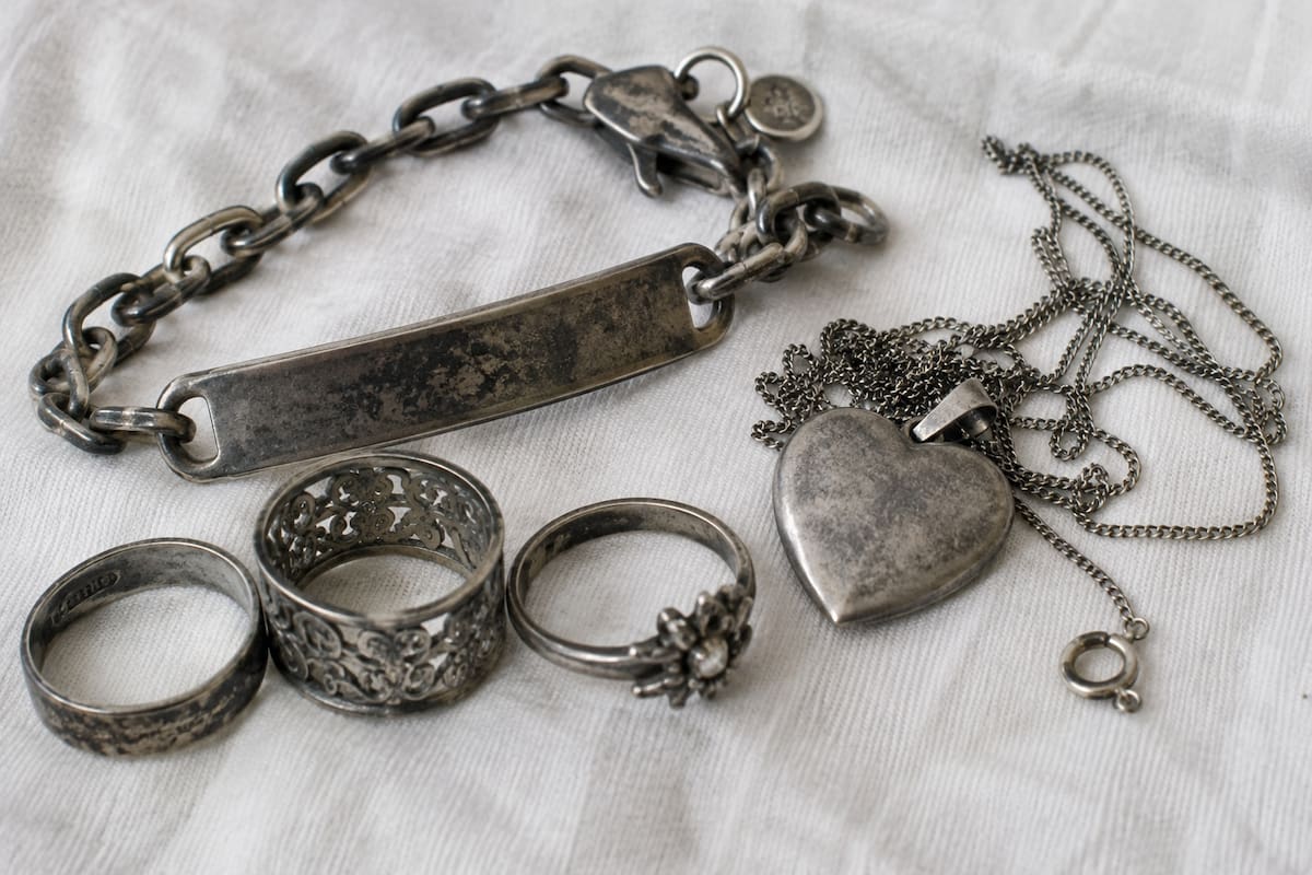 Joyería de plata con manchas oscuras y pérdida de brillo, señales comunes del deslustre que aparece por reacciones químicas en la superficie del metal. | Imagen hecha con ChatGPT