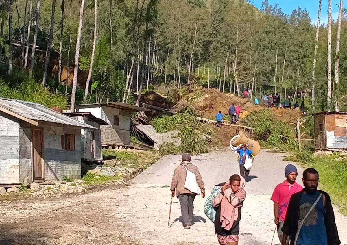 La gente camina con sus pertenencias en la zona donde un deslizamiento de tierra azotó la aldea de Kaokalam, provincia de Enga, Papúa Nueva Guinea, el 24 de mayo de 2024.