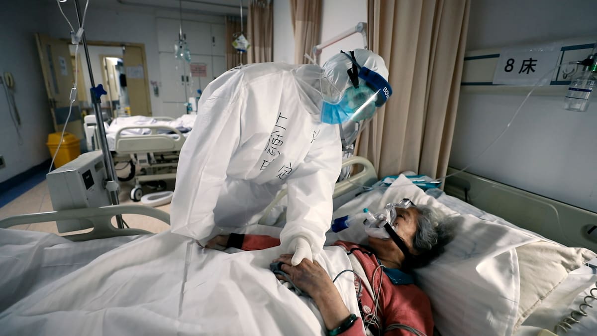 Una mujer mayor con COVID-19 es reconfortada por un doctor en un hospital en Wuhan, China en una escena del documental "76 Days". El filme realizado en hospitales de Wuhan captura el horror local antes de que se volviera una pesadilla mundial. (MTV Documentary Films via AP)