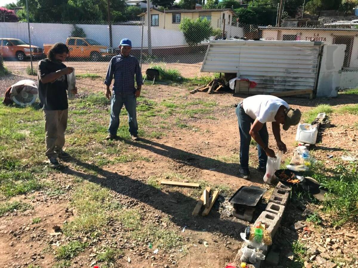 Algunos migrantes que esperan en Nogales tratan de descansar un poco mientras llegan sus empleadores y otros se preparan alimentos al aire libre.