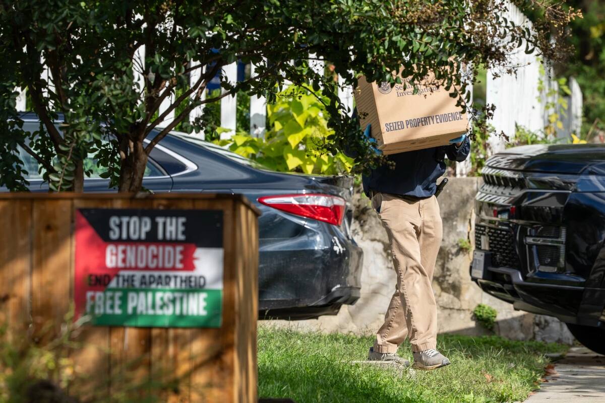 Se observan carteles en la propiedad de un vecino de la representante Ilhan Omar (demócrata por Minnesota) el lunes 12 de octubre de 2026, mientras agentes del Departamento de Seguridad Nacional transportan cajas durante un registro de la residencia de Omar en Washington. (Foto AP/J. Scott Applewhite)
