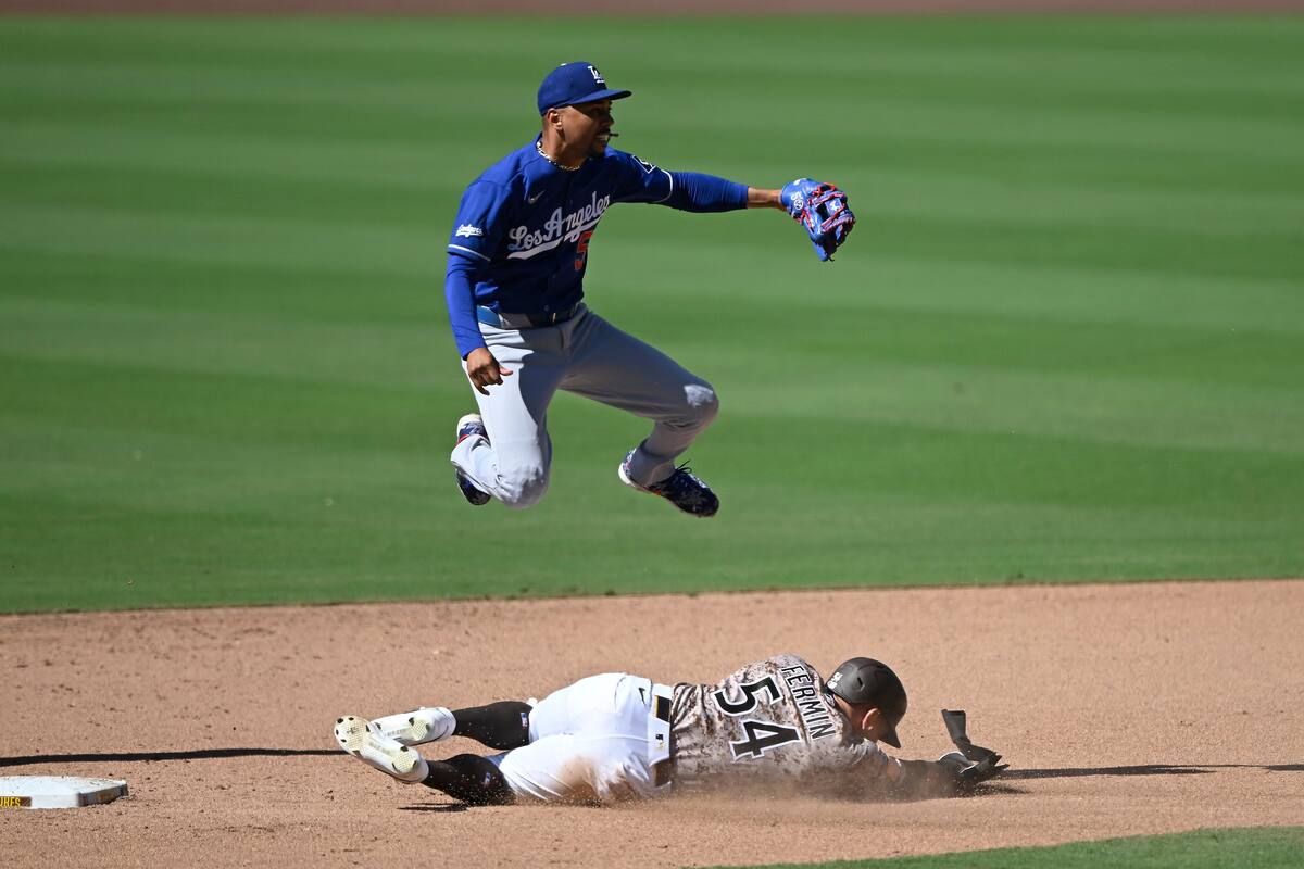 Mookie Betts, arriba, de los Dodgers de Los Ángeles, salta sobre Freddy Fermin (54), de los Padres de San Diego, luego de lanzar a primera para completar un double play durante la novena entrada del juego de béisbol de Grandes Ligas del domingo 28 de junio de 2026, en San Diego. (AP Foto/Denis Poroy)
