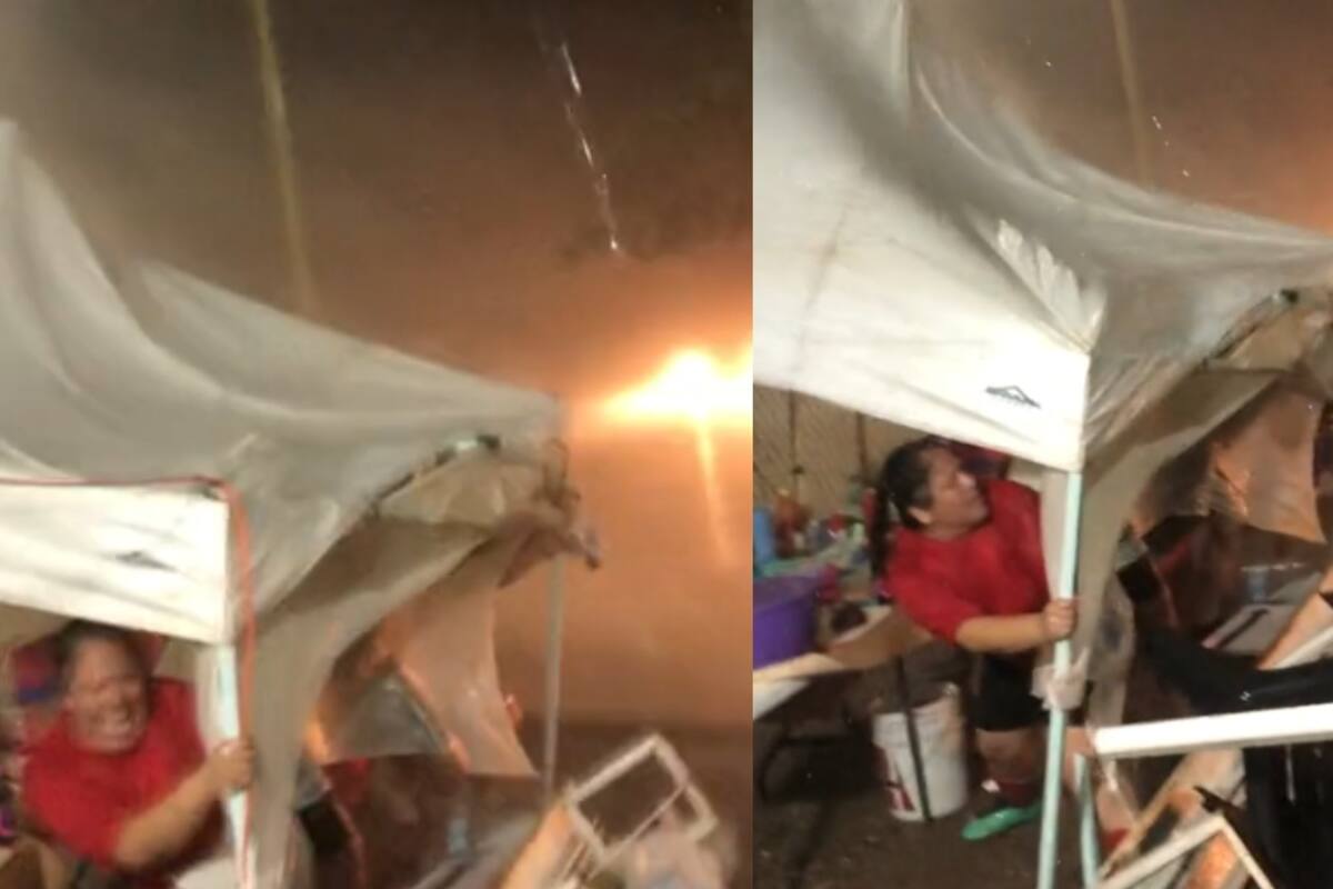 Un puesto ambulante fue azotado por la lluvia, y el hombre tuvo que sujetar su carpa para que no saliera volando