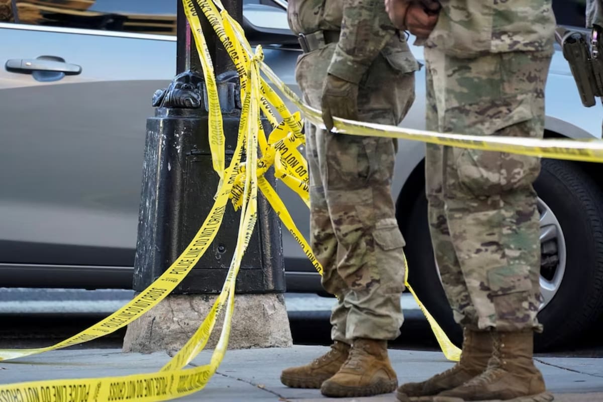 National Guard members stand together behind yellow tape, after two National Guard members were shot near the White House in Washington, D.C., U.S., November 26, 2025.