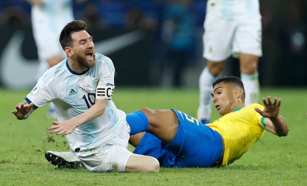 El delantero argentino Lionel Messi es derribado por el brasileño Casemiro en la semifinal de la Copa América, en Belo Horizonte, Brasil, el martes 2 de julio de 2019. (AP Foto/Víctor R. Caivano)