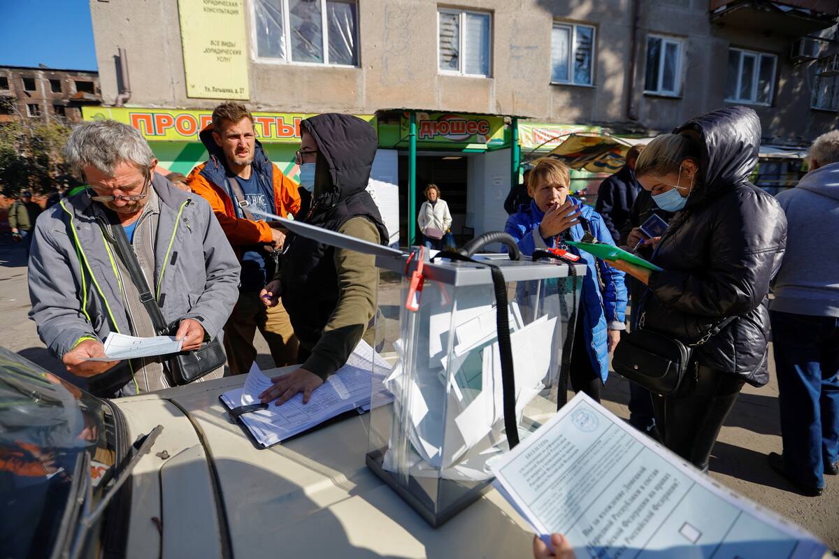 La gente se reúne alrededor de una urna electoral móvil en el tercer día de un referéndum sobre la unión de la autoproclamada República Popular de Donetsk (RPD) a Rusia, en Mariúpol, Ucrania. 25 de septiembre, 2022. REUTERS/Alexander Ermochenko