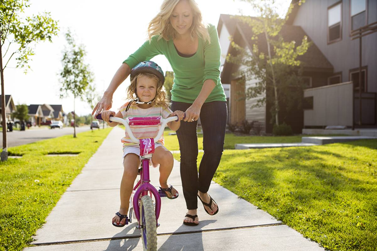 Mother teaching her daughter how to ride a bicycle.