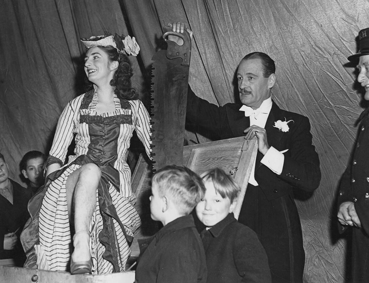 British stage magician Jasper Maskelyne (1902 - 1973) prepares to saw assistant Maisie Wright in half at the Whitehall Theatre in London, 1948. (Photo by London Express/Hulton Archive/Getty Images)