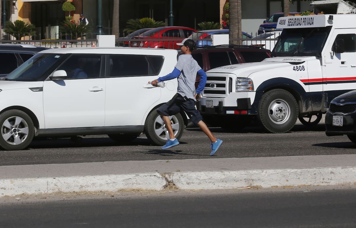 Un joven "limpiavidrios" corre de prisa al ver llegar vehículos de paisanos para realizar su labor en el cruce de Enrique Mazón López y Periférico Oriente en la salida norte de la ciudad. | Banco digital GH