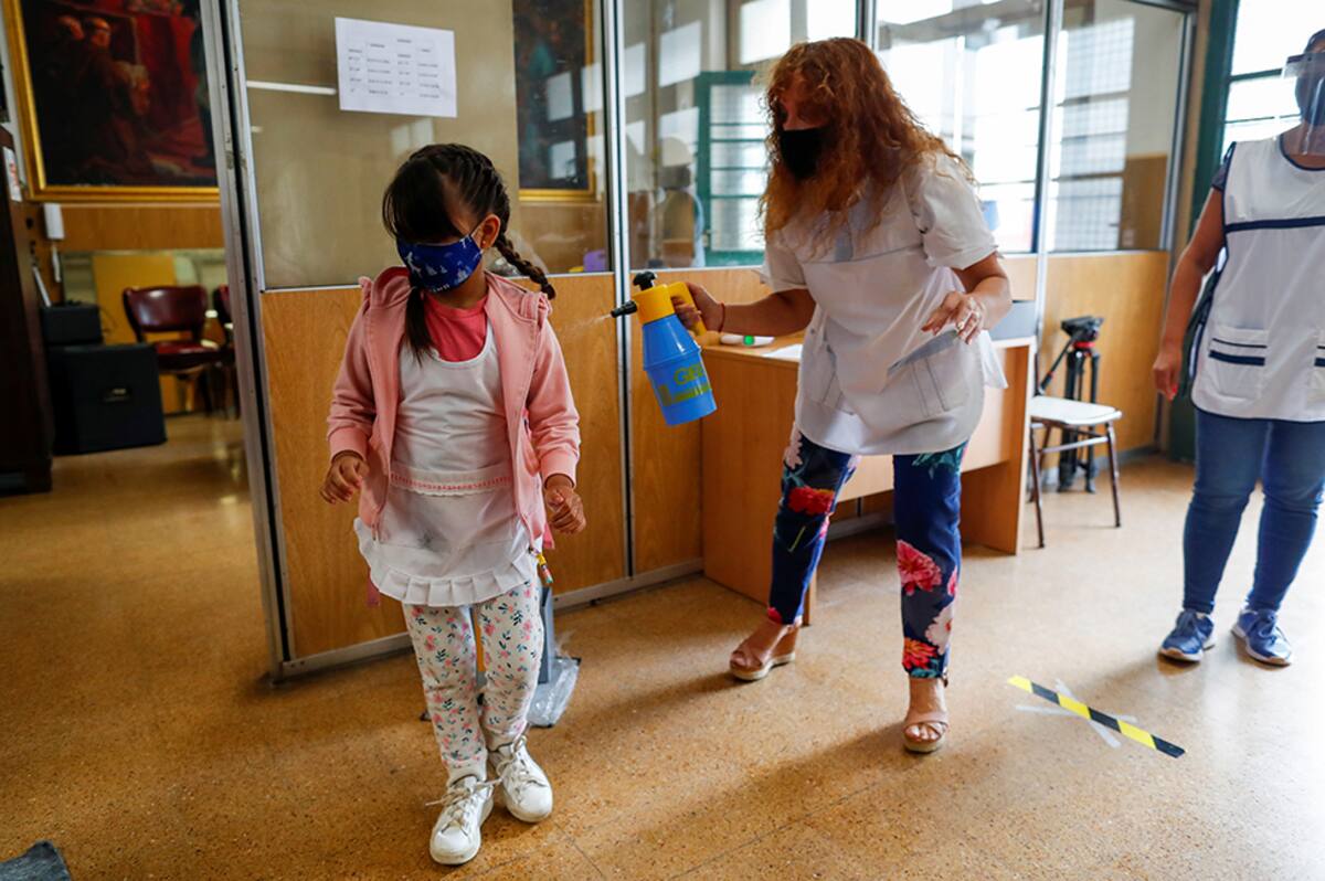 A school director, Marcela Durak, disinfects a girl at their school during the first day of the reactivation of face-to-face classes, as the outbreak of the coronavirus disease (COVID-19) continues, in Buenos Aires, Argentina February 17, 2021. REUTERS/Agustin Marcarian