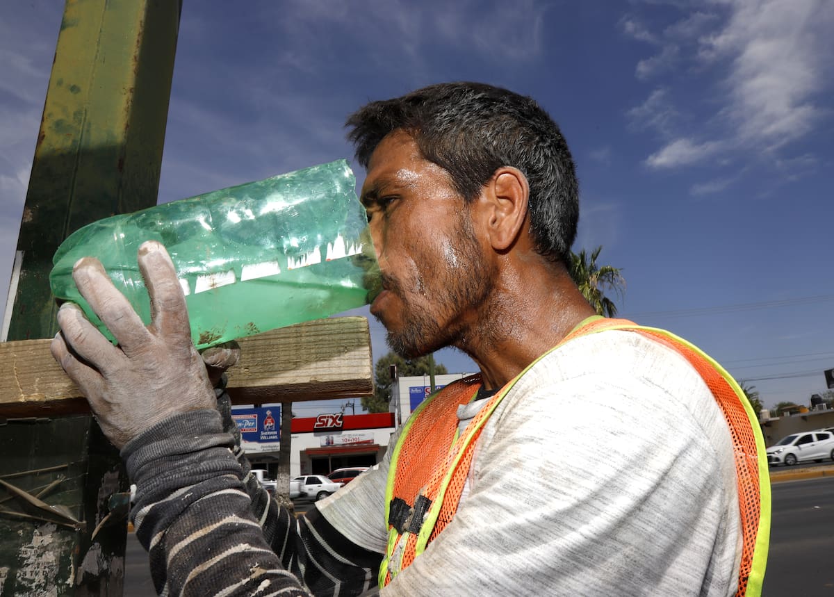 Trabajador toma agua para rehidratarse ante el intenso calor.