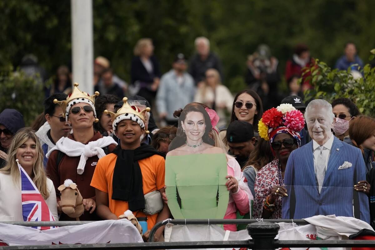 Fanáticos de la realeza británica sostienen imágenes del rey Carlos III, y de la princesa de Gales, Catalina, durante el desfile por el cumpleaños del rey en Londres. | AP