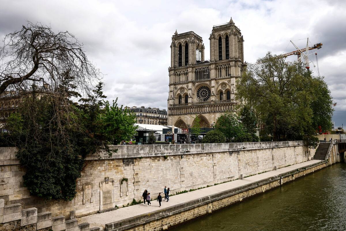 Paris (France), 15/04/2024.- People walk on the bank of the Seine river with the Notre-Dame Cathedral seen in the background, in Paris, France, 15 April 2024. Five years on since the collapse of the Notre-Dame cathedral's spire in a devastating fire on 15 April 2019, its reopening is scheduled for December 2024, according to Philippe Jost, president of the public body overseeing its reconstruction. (Francia) EFE/EPA/MOHAMMED BADRA