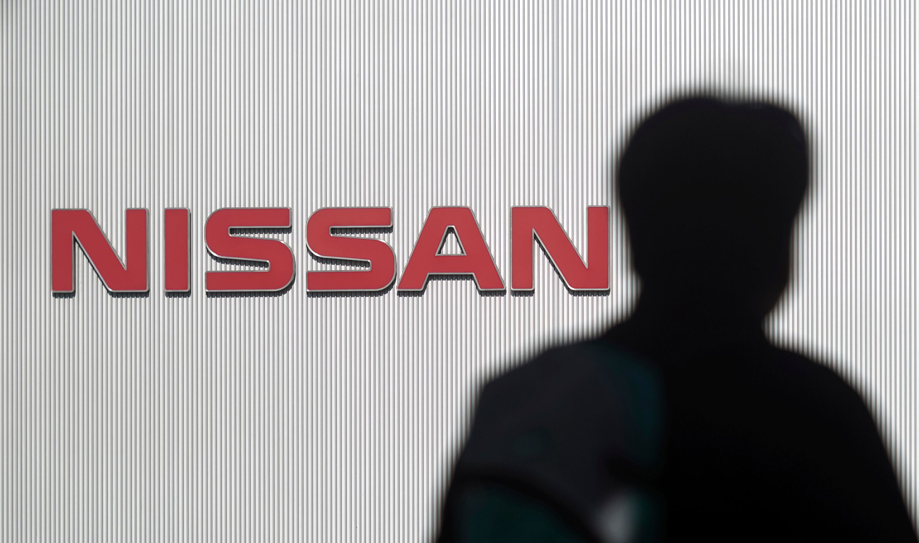 A man walks past the logo of Nissan Motor Co. at Nissan Motor Co. Global Headquarters in Yokohama near Tokyo Wednesday, Nov. 21, 2018. France