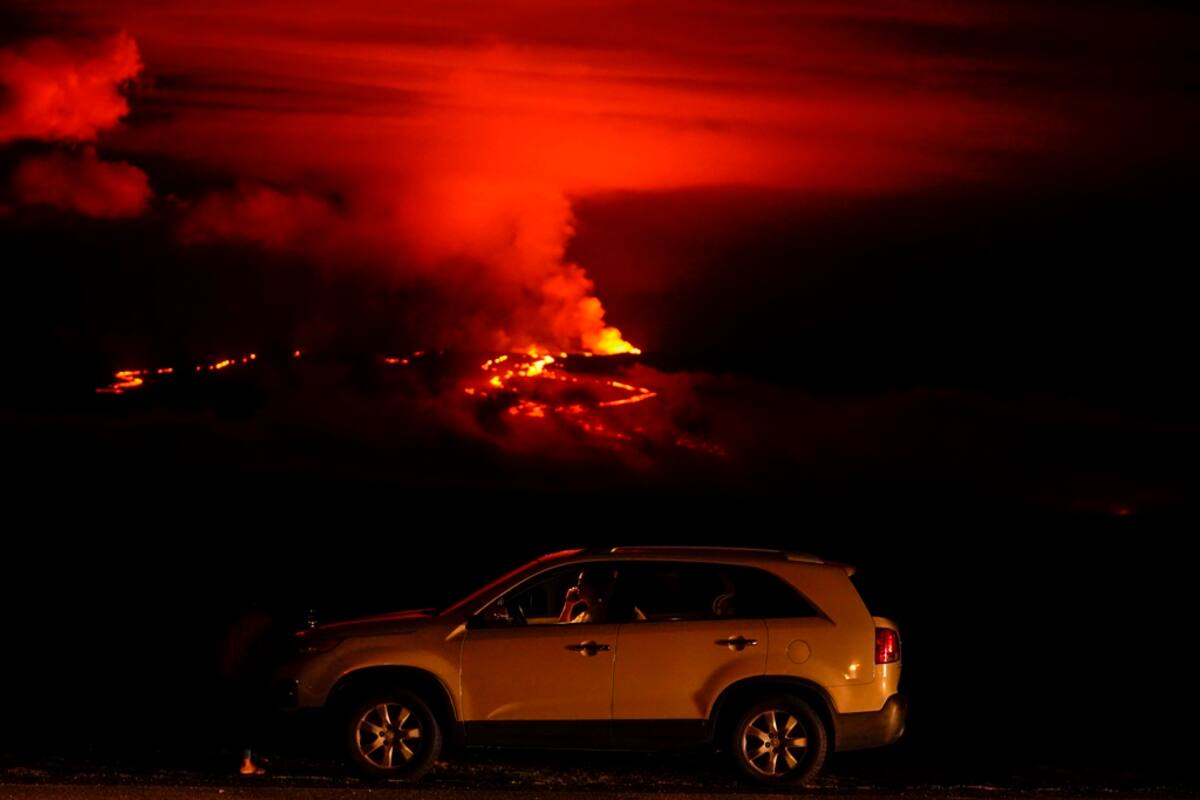 Un hombre conversa por teléfono desde su auto a lo largo de Saddle Road, la principal carretera que une las costas este y oeste de la Isla Grande de Hawai, al tiempo que el volcán Mauna Loa hace erupción el miércoles 30 de noviembre de 2022, cerca de Hilo, Hawai. (AP Foto/Gregory Bull) Ilustrativa para esta nota.