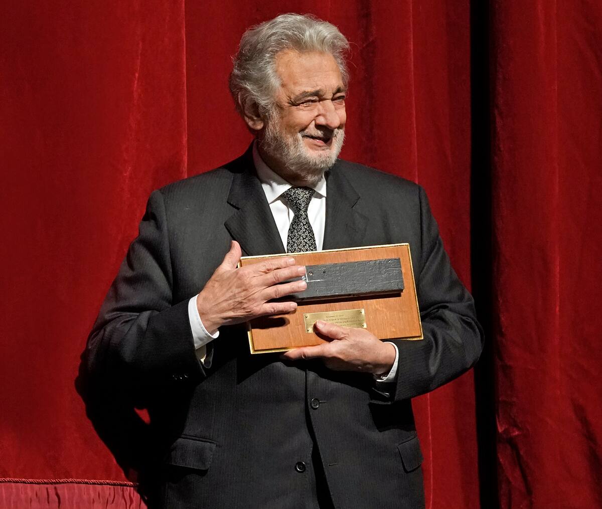 In this photo provided by the Metropolitan Opera, Placido Domingo stands on stage with one of the special gifts he was presented with during a special anniversary celebration: a piece of the Metropolitan Opera stage, at the Metropolitan Opera, Friday, Nov. 23, 2018, in New York. Domingo celebrated the 50th anniversary of his debut at the Met. (Ken Howard/Metropolitan Opera via AP)