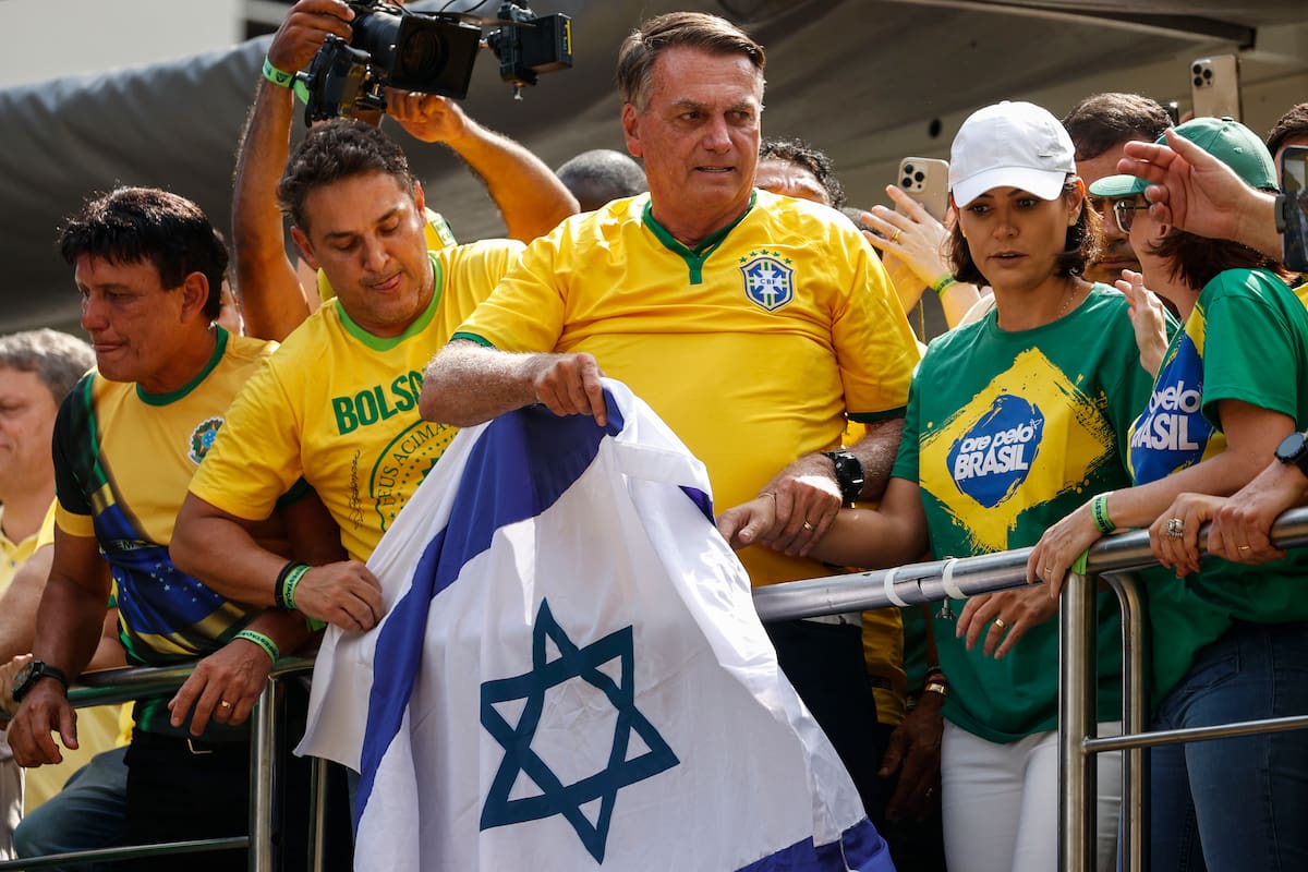 AME2288. SAO PAULO (BRASIL), 25/02/2024.- El expresidente brasileño Jair Bolsonaro (c) (2019-2022), acompañado de su esposa, Michelle (2d), sostiene una bandera israelí durante una movilización en la que reunió a miles de seguidores para darse su primer baño de masas desde que dejó el poder a finales de 2022, y defenderse de las investigaciones por un supuesto intento de golpe de Estado, este domingo, en Sao Paulo (Brasil). Subido a un camión instalado en plena Avenida Paulista, la más emblemática de la ciudad, Bolsonaro negó la existencia de una trama golpista, se dijo víctima de una persecución, y criticó los abusos de algunos. EFE/ Sebastiao Moreira