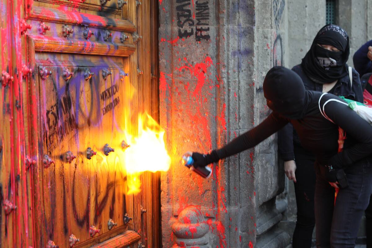 Por feminicidios, mujeres pintan fachada y puerta de Palacio Nacional