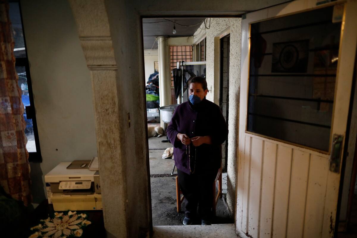 Leticia Pinera Santana está de pie afuera de una casa mientras reza por su suegro, Manuel Briseno, de 78 añor, quien murió el martes por complicaciones por el nuevo coronavirus en el barrio de Iztapalapa en Ciudad de México el miércoles 22 de abril de 2020. (AP Foto/Rebecca Blackwell)