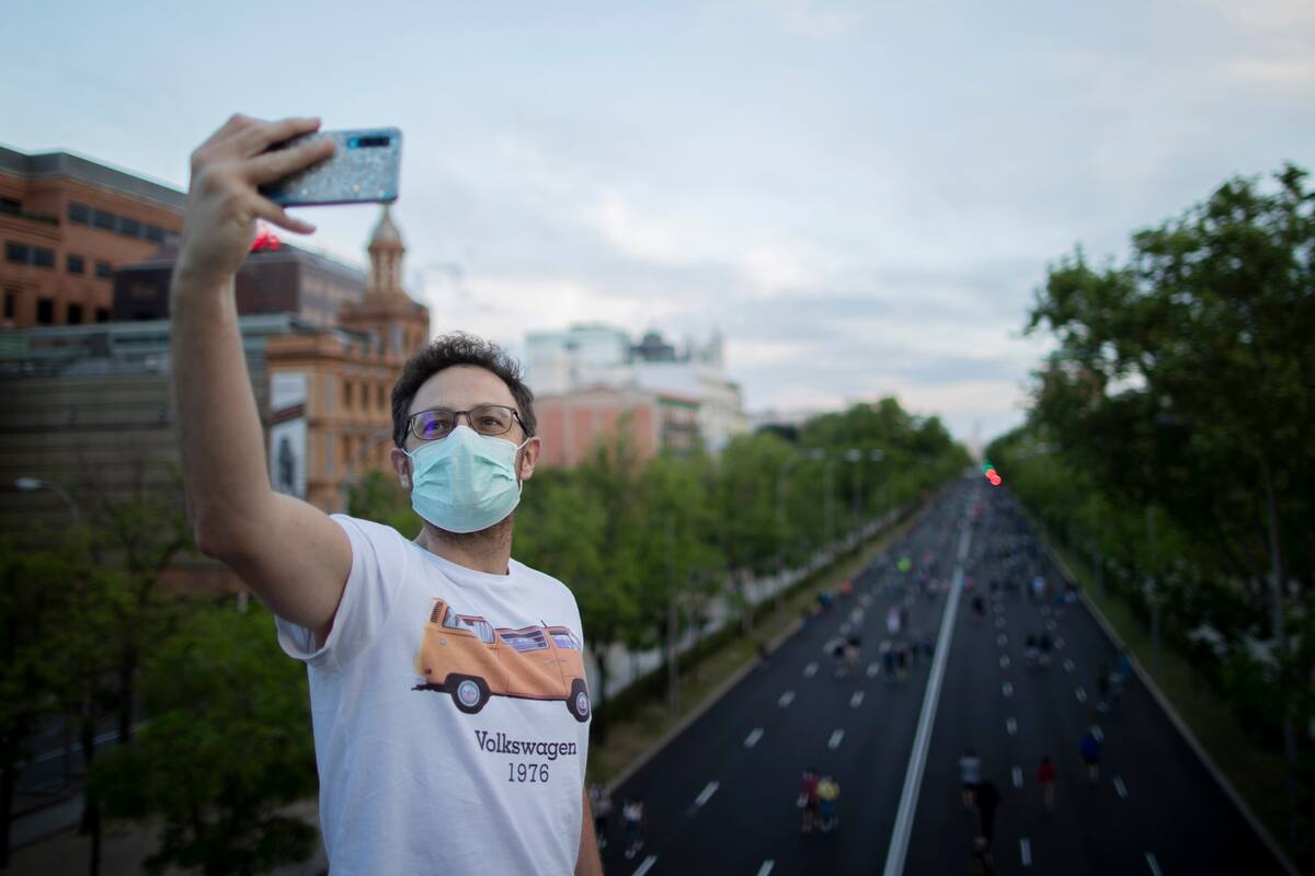 Un hombre se toma una foto con el Paseo de la Castellana de fondo en Madrid, España, el 9 de mayo de 2020. (AP Foto/Manu Fernandez)