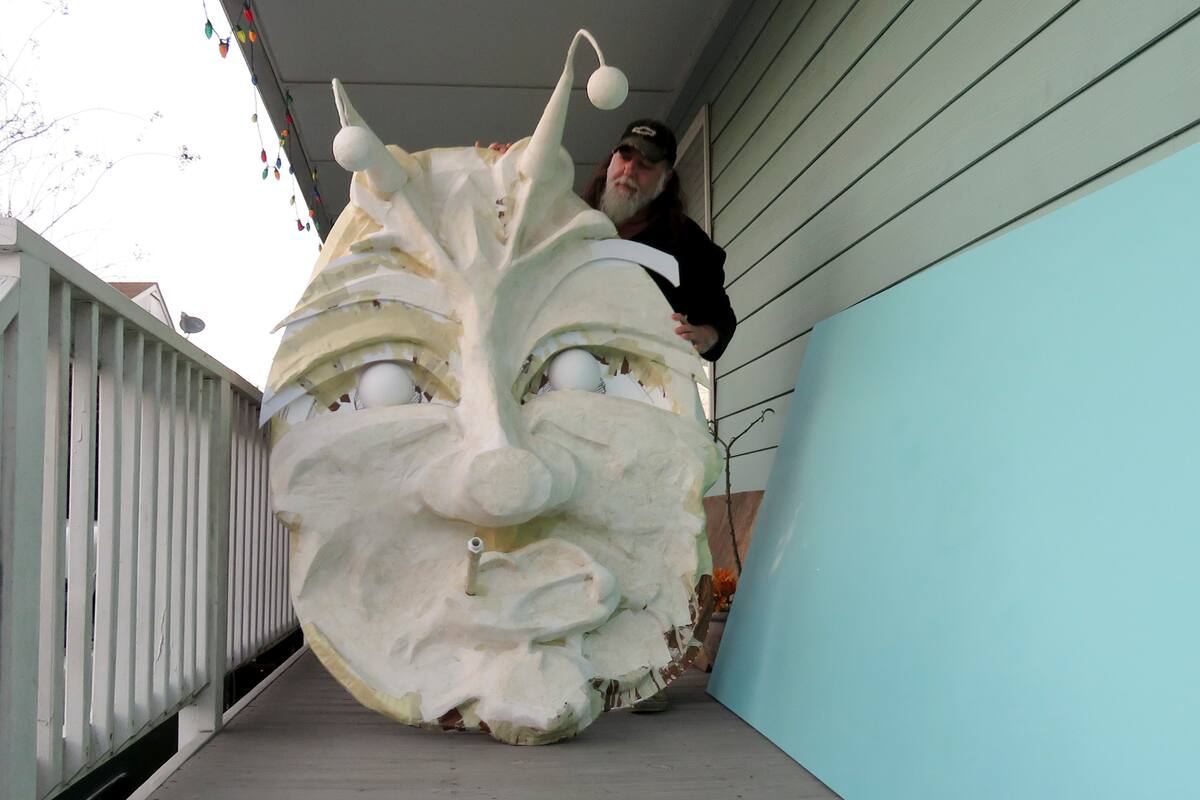 Thom Karamus muestra su cabeza de papel maché de la oruga fumadora de "Alicia en el País de las Maravillas", el miércoles 14 de enero del 2021 en Nueva Orleans. Con la cancelación de los tradicionales desfiles de Mardi Gras debido a la pandemia de coronavirus, miles alrededor de la ciudad han decorado sus casas para celebrar el Carnaval. (AP Foto/Janet McConnaughey)