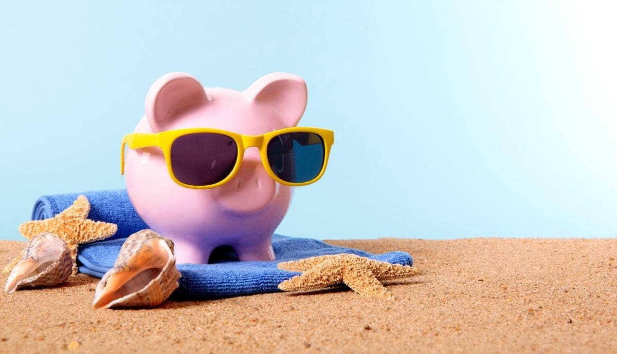 Halcancía en forma de cerdo con lentes de sol sobre una toalla de playa, en una representación del ahorro para vacaciones. | Magnific