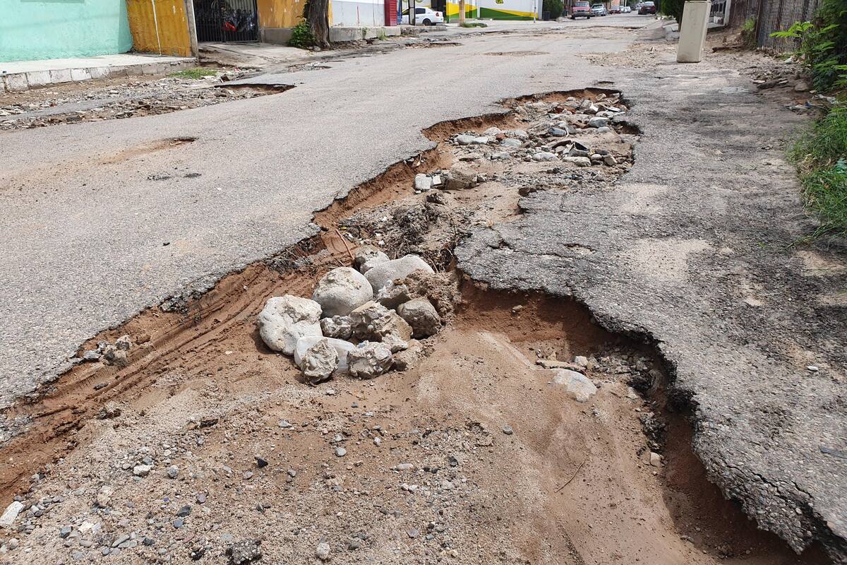 Vecinos rellenan hoyos con arena en la calle Huachinera
