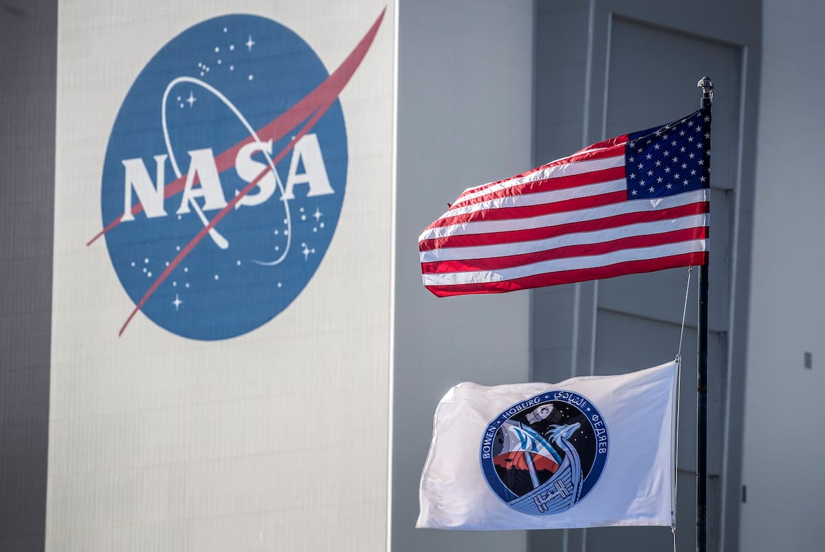 Titusville (Estados Unidos), 26/02/2023.- Las banderas de EU y Crew-6 se ven frente al edificio de ensamblaje de vehículos de la NASA, horas antes del lanzamiento programado del cohete SpaceX Falcon 9. La NASA cumple 65 años de su creación. | Crédito: EFE/EPA/CRISTOBAL HERRERA-ULASHKEVICH