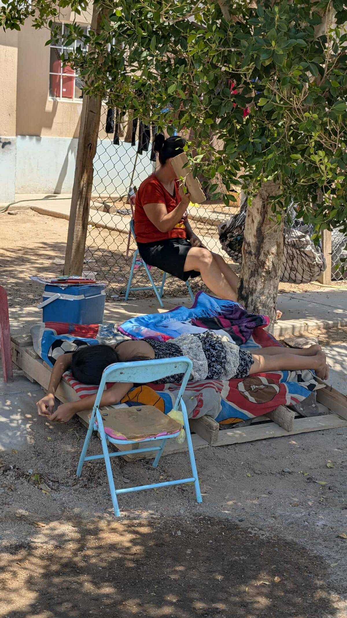 Josefina Brito le echar aire a su nieta con un cartón mientras que su otra nieta descansa en un colchón en la Cerrada Diamante de Paseoo del Pedregal, los vecinos no tiene luz desde ayer Martes. / Imagen por Julián ortega.