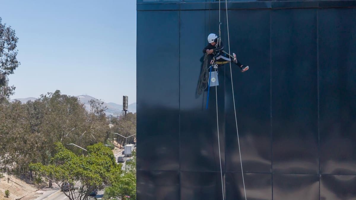 El trabajador realizaba labores de limpieza en la fachada del edificio cuando una cuerda presentó una falla; su sistema de seguridad evitó una caída y permitió que descendiera sin lesiones. Foto: Border Zoom.