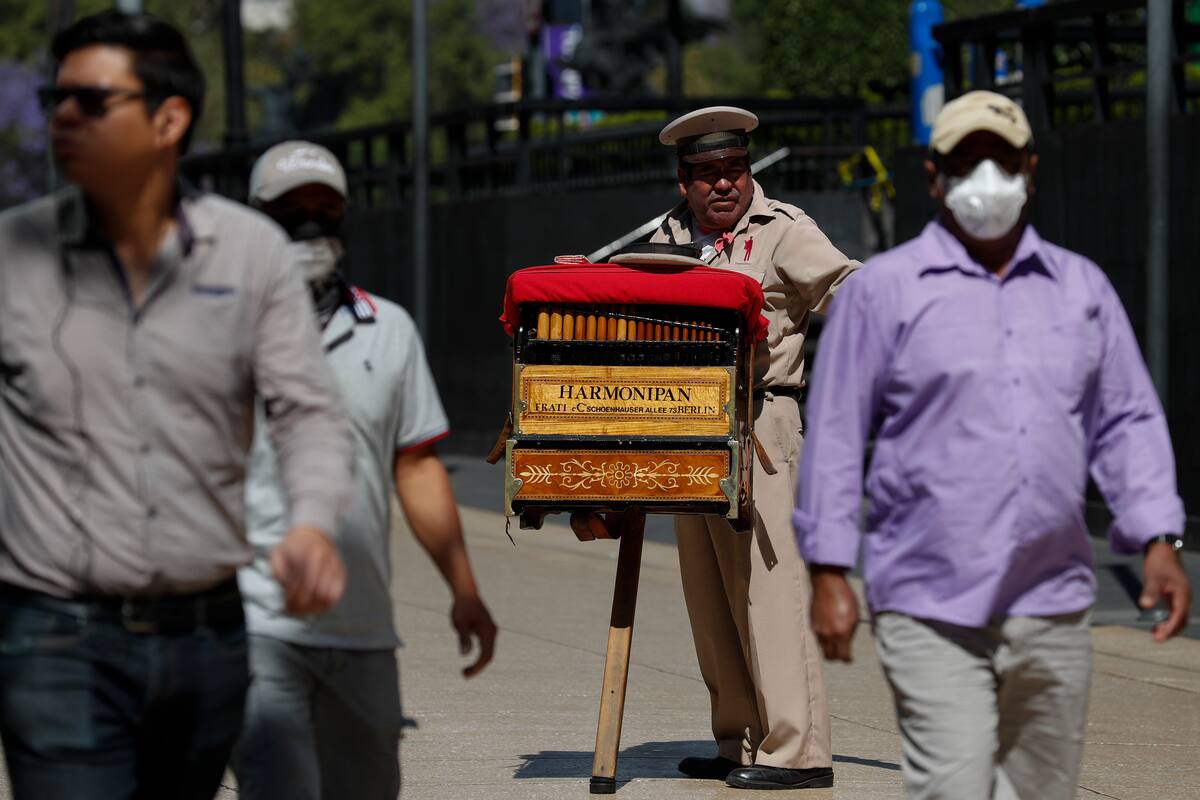 El organillero Moisés Rosas pide propinas a los peatones en el centro de Ciudad de México, el martes 24 de marzo de 2020. Rosas que lleva 25 años como organillero, dijo no tener miedo al nuevo coronavirus y necesita los 200 pesos (unos 8,50 dólares) de media que gana al día. Su familia vive al día, señaló, de modo que si no trabajan, no tendrán ingresos. (AP Foto/Rebecca Blackwell)