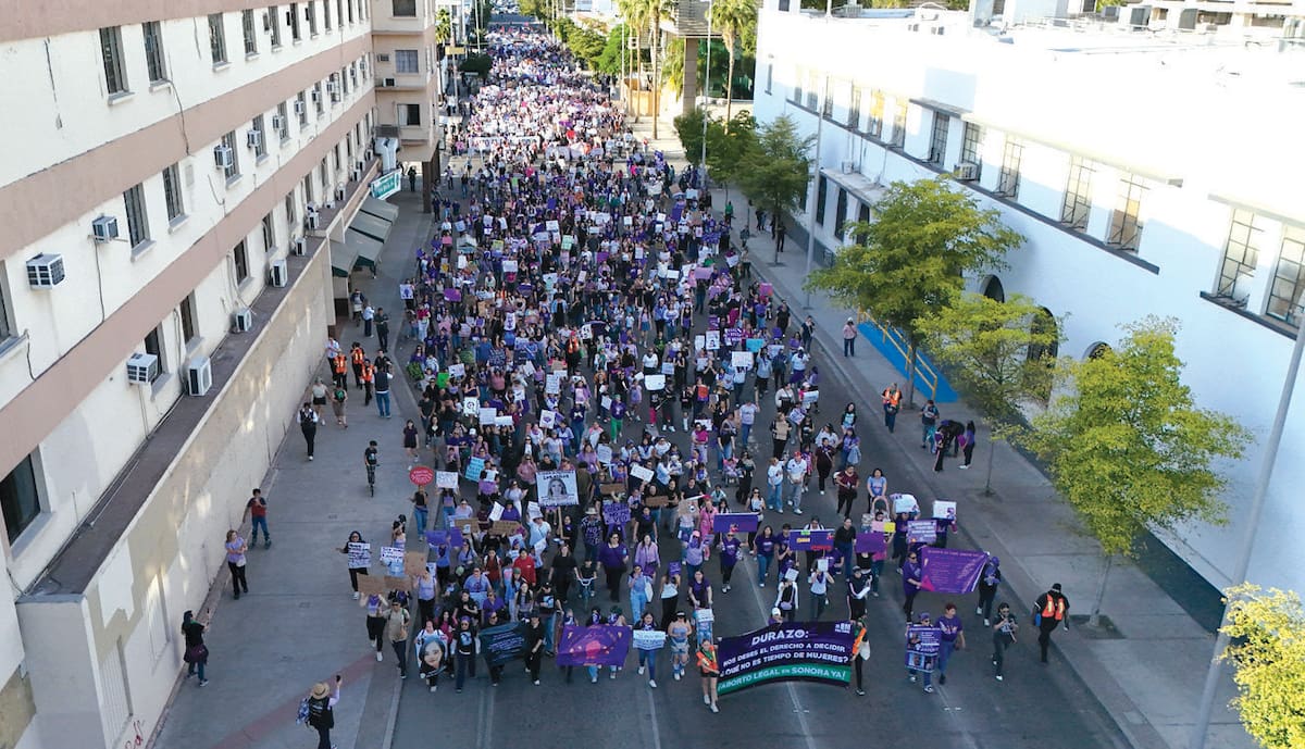 Personas que participaron ayer en la marcha por el Día Internacional de la Mujer en Hermosillo caminan a lo largo de la calle Rosales. FOTO: ERNESTO LUGO