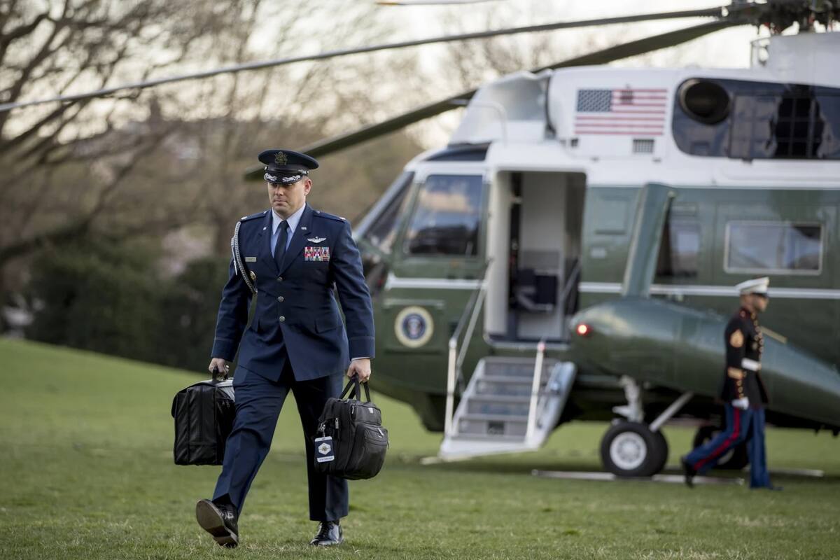ARCHIVO - Un asistente militar de EU lleva la Mochila de Emergencia Presidencial a través del Jardín Sur de la Casa Blanca en Washington, el domingo 31 de marzo de 2019, mientras regresa con el presidente Donald Trump y la primera dama Melania Trump a Washington, desde su finca Mar-a-Lago en Florida. | Crédito: AP/Andrew Harnik, Archivo