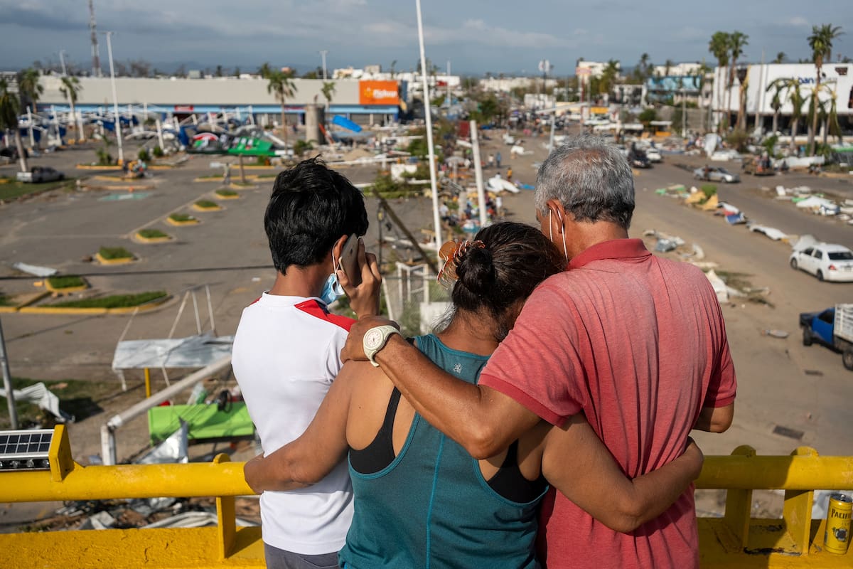 Pobladores, en un paso elevado, miran los daños causados por el huracán Otis, de categoría 5, en Acapulco, México, el viernes 27 de octubre de 2023. (AP Foto/Félix Márquez)