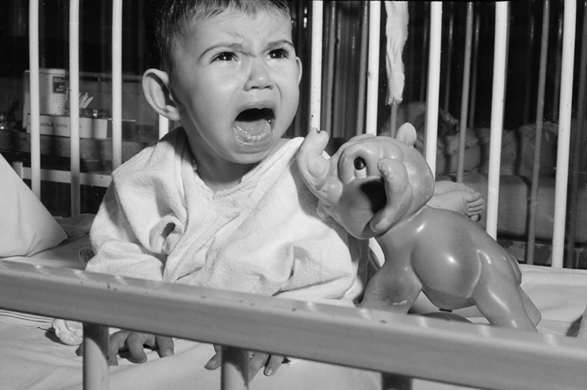 A very unhappy toddler screams in his crib